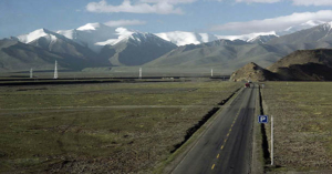 Vehicles travel on a highway as the first Beijing-to-Tibet train passes along the Qinghai-Tibet railway July 3, 2006. The 4,000-km (2,500-mile) journey will reach altitudes of over 5,000 metres (16,400 feet) on the Tibetan plateau. - PBEAHUNLNDR